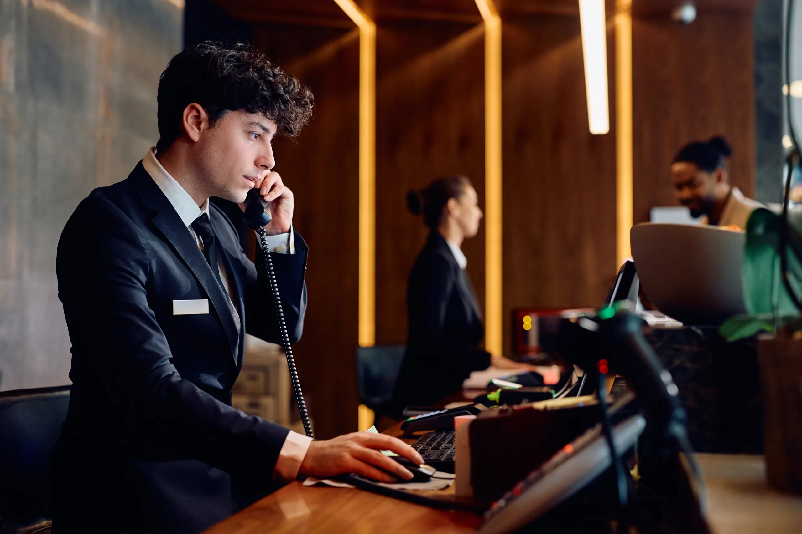 Young,Receptionist,Making,A,Phone,Call,While,Working,On,Desktop Hospitality_2